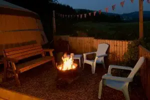 Ty crwn mawr yurt outside covered dining area and firepit nighttime and evening 10 off grid sustainable eco glampsite and glamping