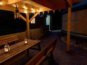 Ty crwn mawr yurt outside covered dining area and firepit nighttime and evening 11 off grid sustainable eco glampsite and glamping