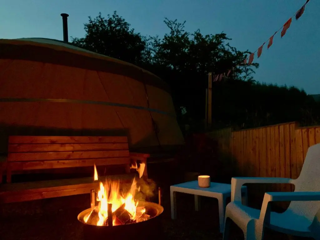 Ty crwn mawr yurt outside covered dining area and firepit nighttime and evening 13 off grid sustainable eco glampsite and glamping