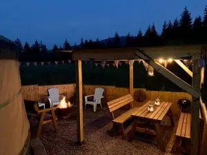 Ty crwn mawr yurt outside covered dining area and firepit nighttime and evening 14 off grid sustainable eco glampsite and glamping