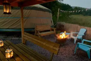 Ty crwn mawr yurt outside covered dining area and firepit nighttime and evening 2 off grid sustainable eco glampsite and glamping