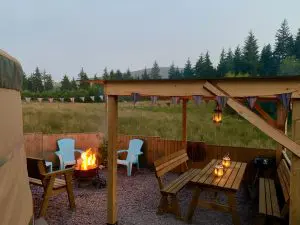 Ty crwn mawr yurt outside covered dining area and firepit nighttime and evening off grid sustainable eco glampsite and glamping