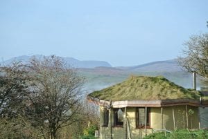 The straw bale roundhouse at ty mam mawr off grid eco retreat centre with arenig fawr and snowdonia national park in the background