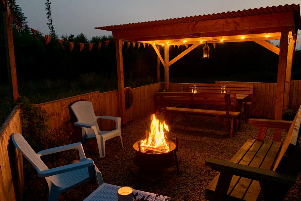 Ty crwn mawr yurt outside covered dining area and firepit nighttime and evening 8 off grid sustainable eco glampsite and glamping